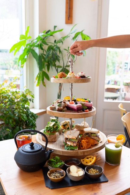 Je ziet een hand die een high tea vastpakt van boven.